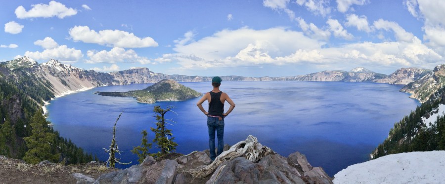 Ich stehe auf einem Vorsprung und blicke auf den dunkelblauen Crater Lake herunter.